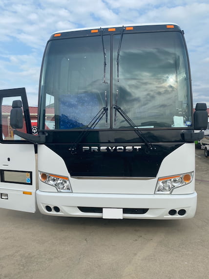 the front of a prevost charter bus parked with the door open