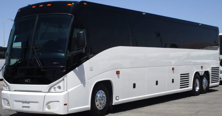 a plain white MCI bus parked on pavement